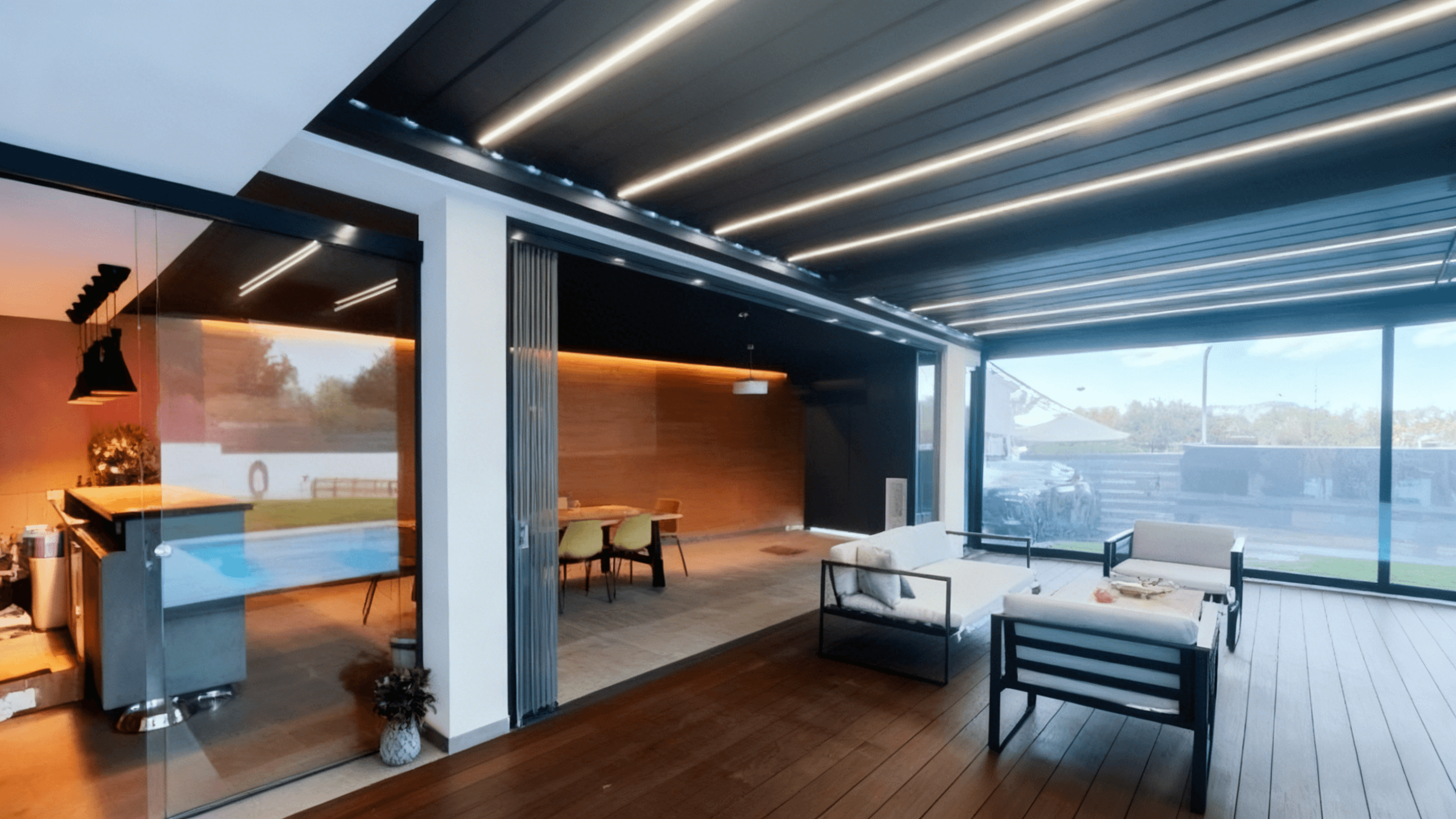 Outdoor kitchen and seating area protected by an aluminum pergola and glass doors